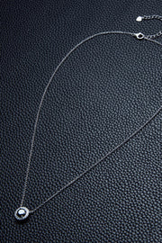 Fine necklace chain laid out on a dark textured surface