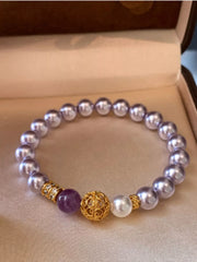 Lavender pearl bracelet with gold filigree and purple accent beads arranged in a jewelry box