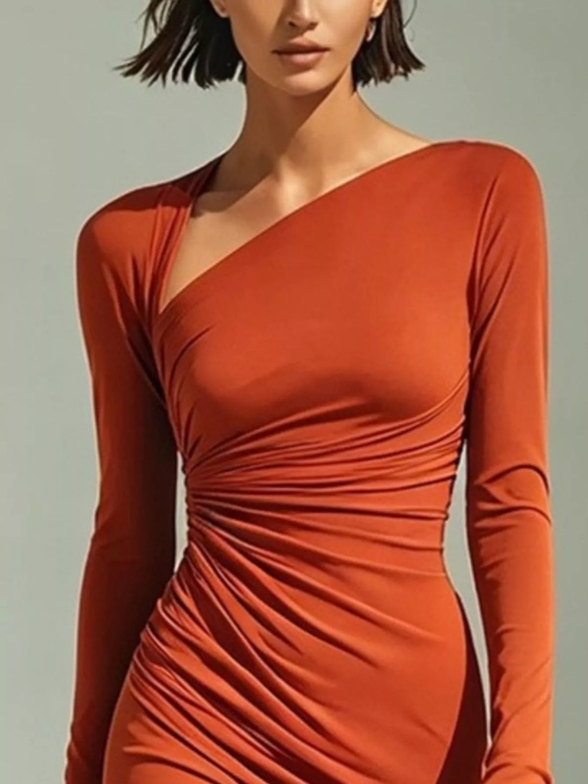 Close-up of the orange dress's diagonal neckline and gathered waist.