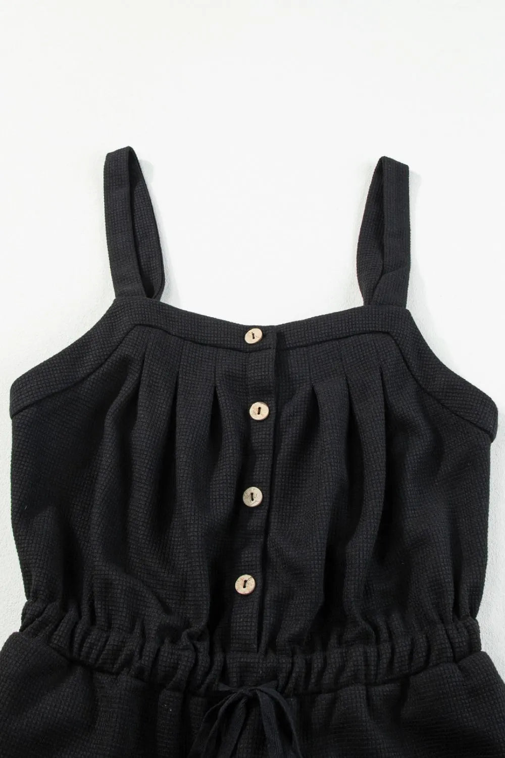 Black jumpsuit bodice showing knotted straps and button placket
