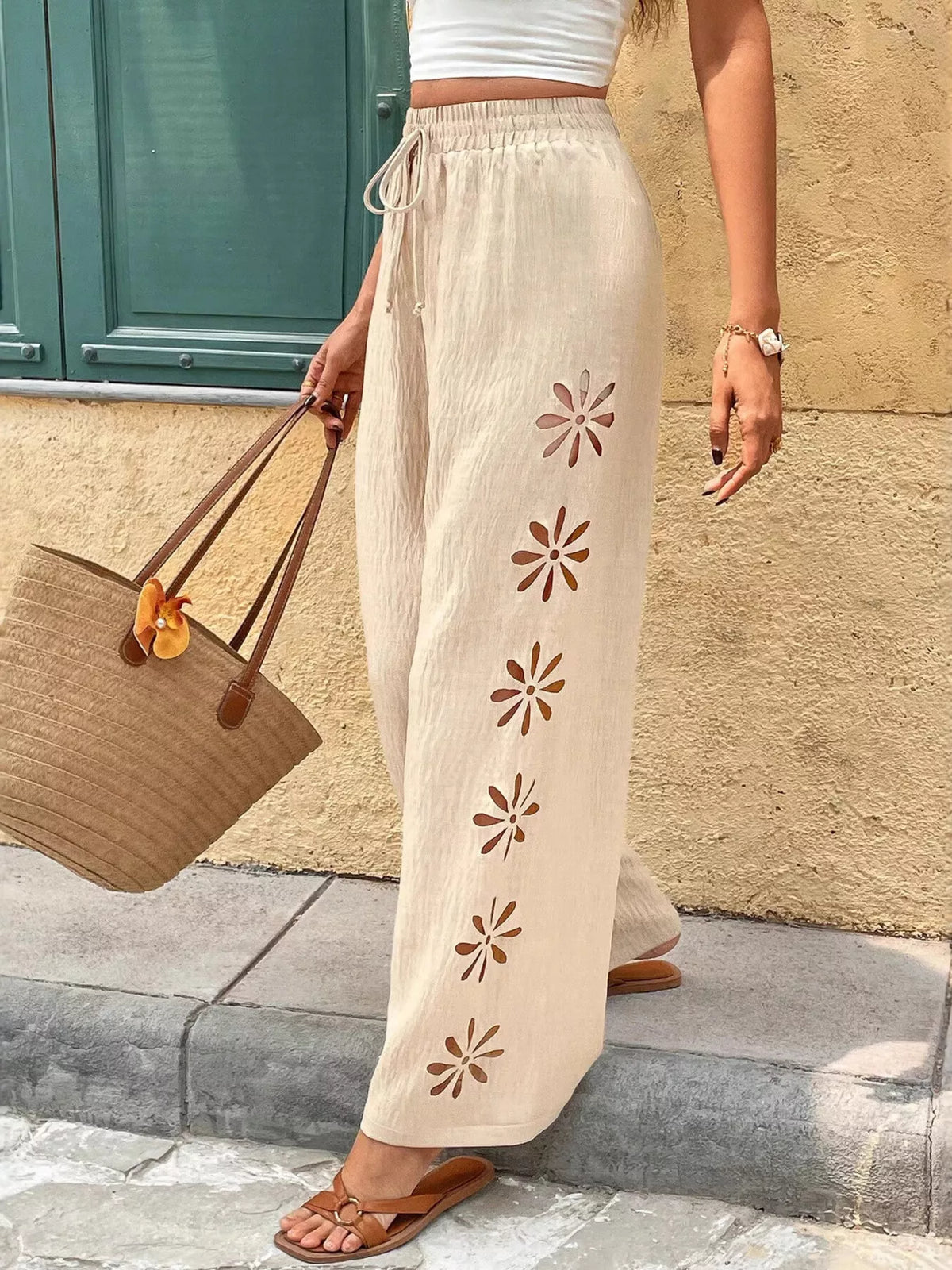 Side view of cream pants with floral cutout details