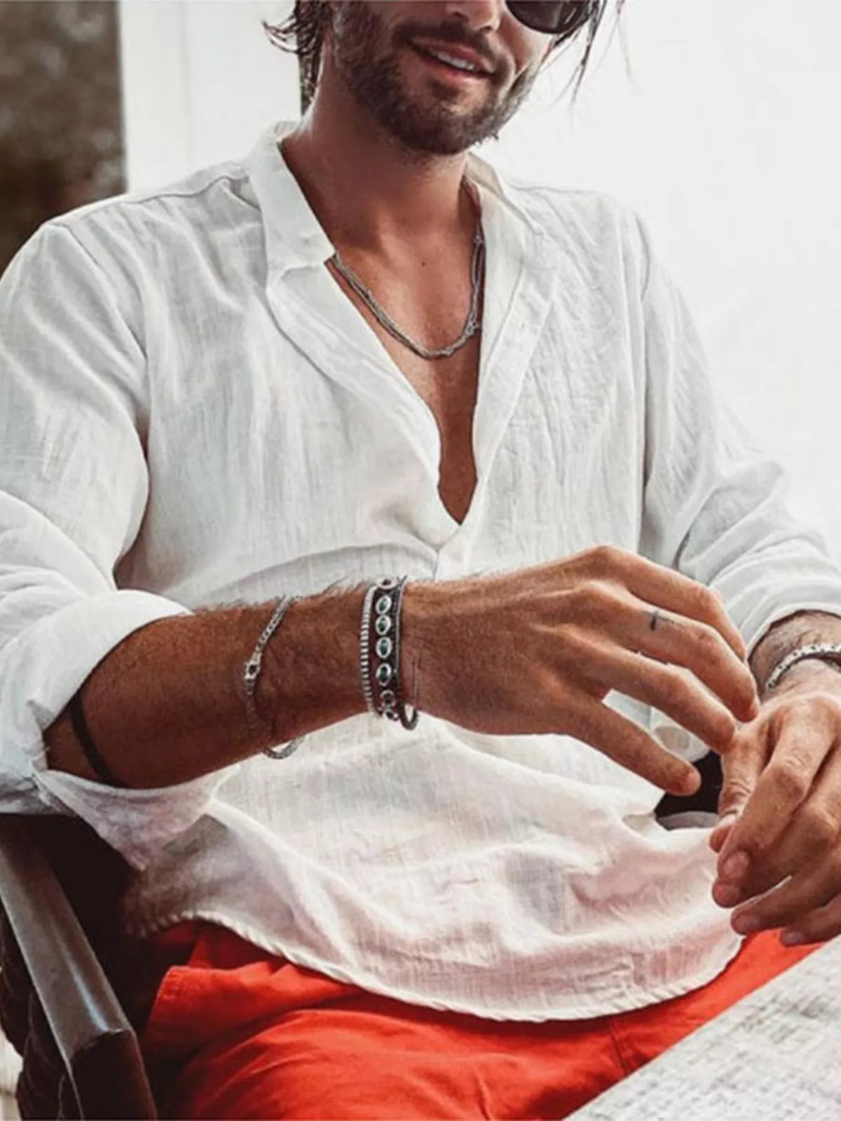 Model seated in a white long-sleeve shirt with sleeves pushed up