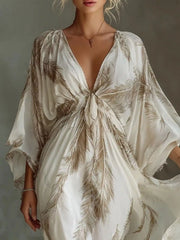 Close view of the brown feather-print maxi dress showing the tied V-neckline and loose sleeves.