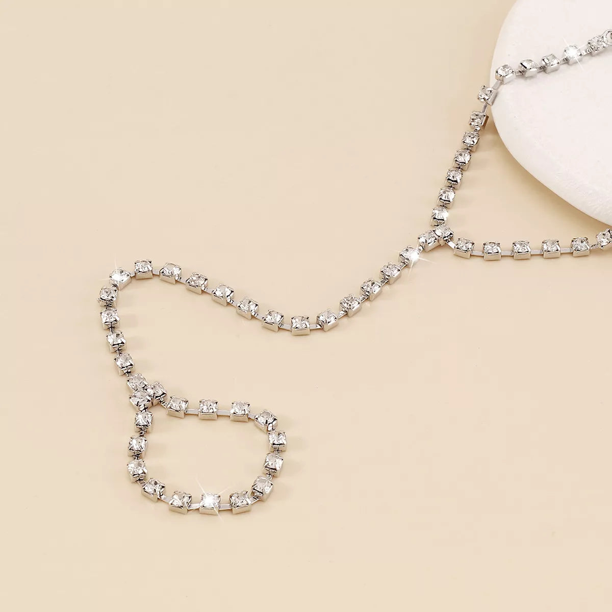 Close-up of rhinestone hand chain and ring on pale background