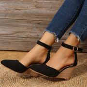 Black pointed-toe sandals shown from the side on feet
