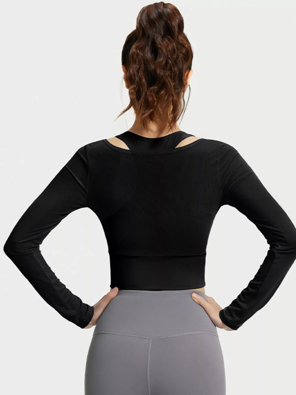 Rear view of black long-sleeve cropped active top with inner racerback shoulder cutouts