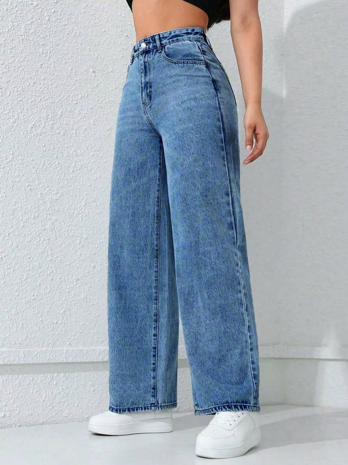 Angled view of blue wide-leg jeans showing the high waist and straight drape