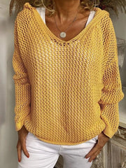 Mustard yellow open-knit hooded cover-up with long sleeves and a V-neck, worn over a white top.