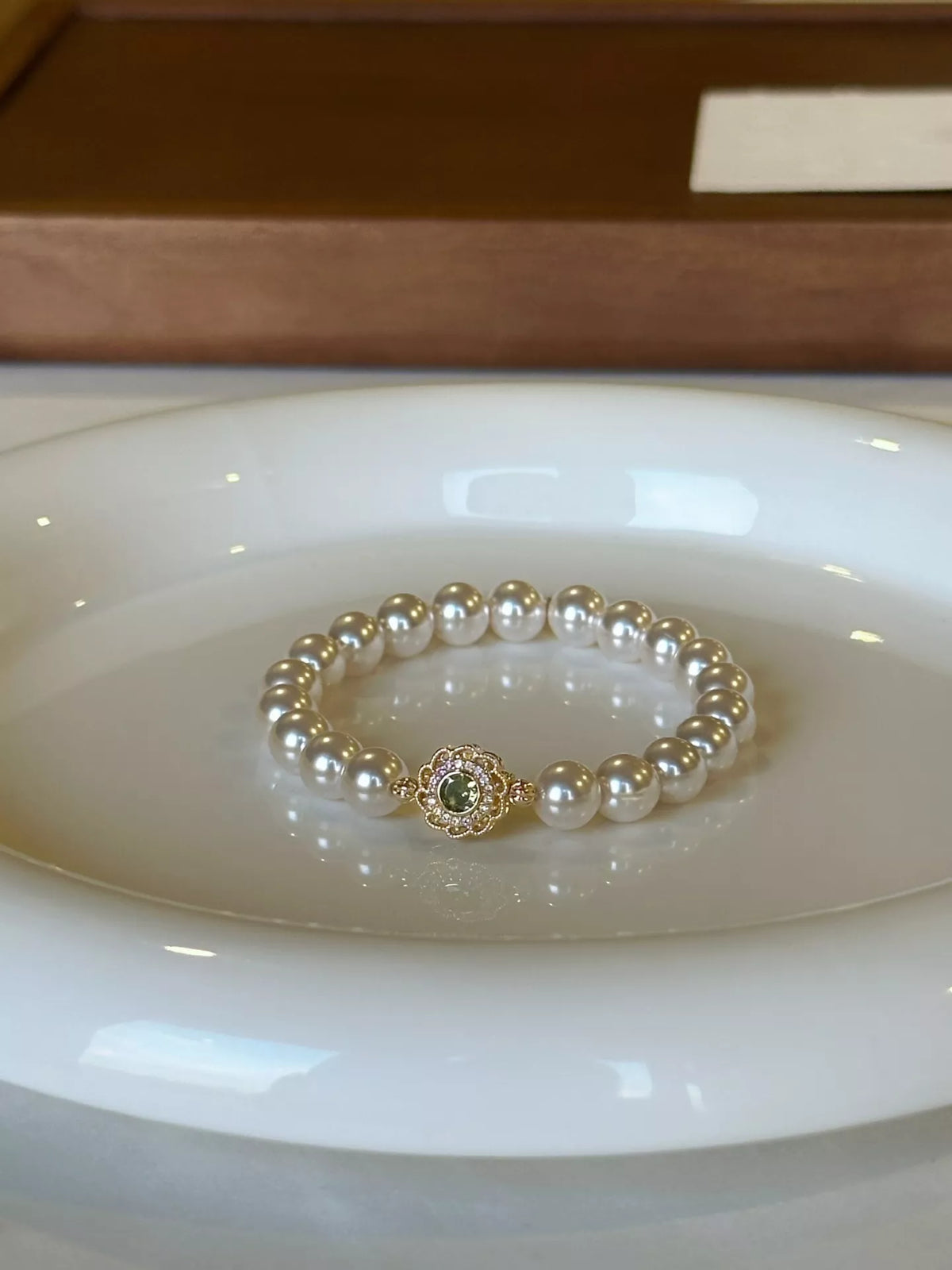 Pearl bracelet with floral charm resting on a white dish