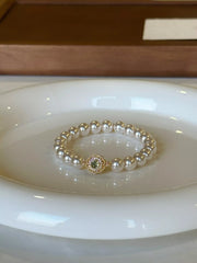 Pearl bracelet with floral charm resting on a white dish