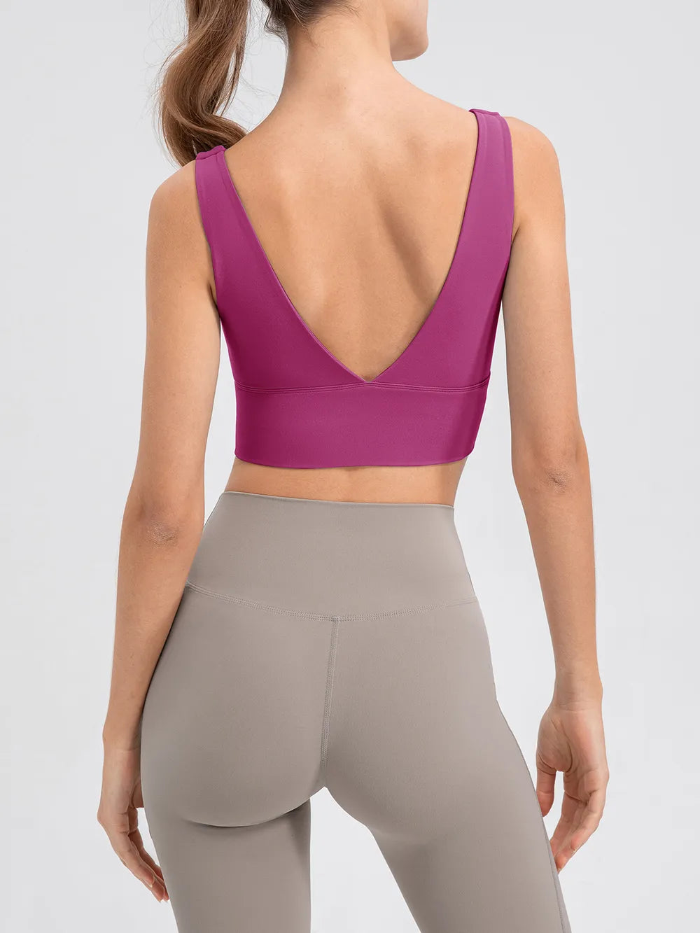 Model wearing the magenta cropped tank with taupe leggings