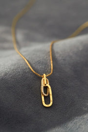 Gold-tone open rectangular pendant necklace on dark background