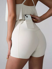 Rear view of cream high-waist active shorts showing a phone in the side pocket.