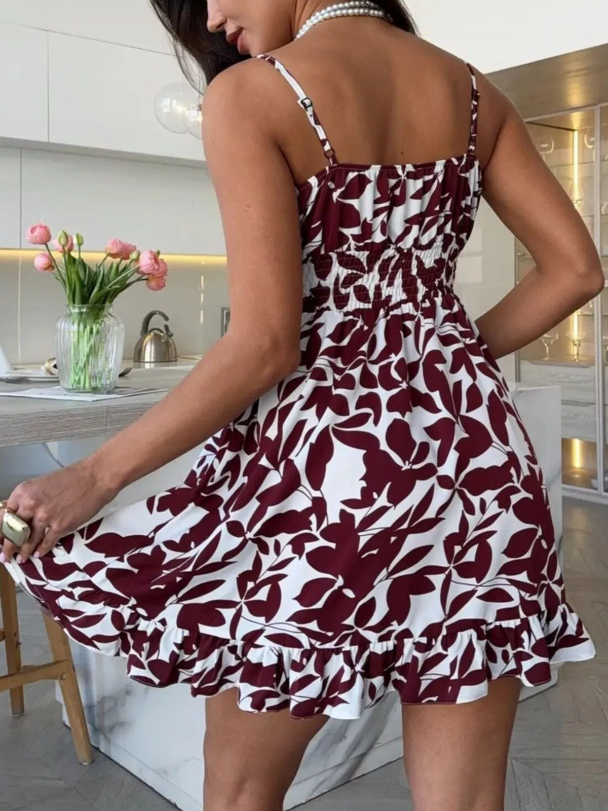 Back three-quarter view of the burgundy abstract-print mini dress with a flared ruffle skirt.