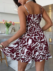 Back three-quarter view of the burgundy abstract-print mini dress with a flared ruffle skirt.