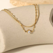 Detail of gold-tone links and clear zircon stones