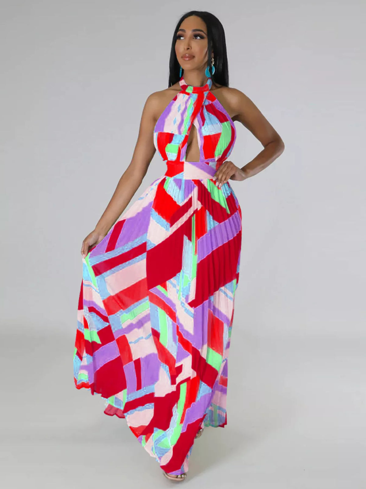 Red and pink geometric halter maxi dress on a model with one hand on her hip and skirt spread to the side.