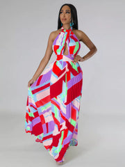 Red and pink geometric halter maxi dress on a model with one hand on her hip and skirt spread to the side.