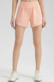 Full front view of peach elastic-waist shorts with curved hems