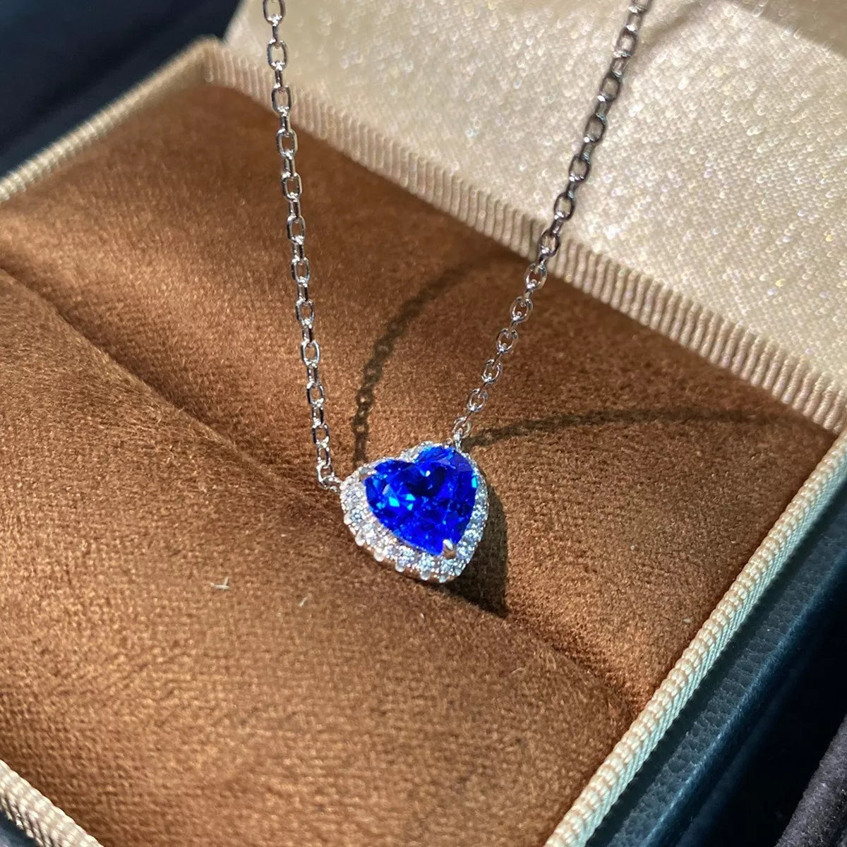 Silver necklace with blue heart-shaped zircon pendant resting in an open jewelry box