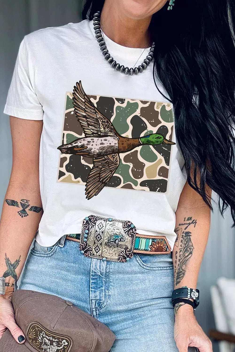 Front view of graphic T-shirt tucked with jeans and western belt