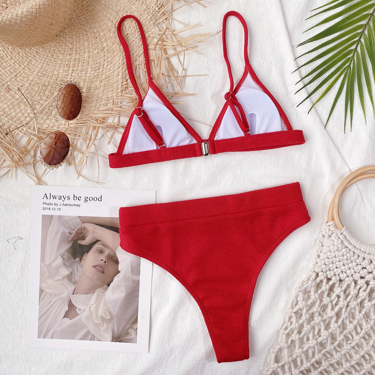 Red ribbed bikini set laid flat with white-lined cups and accessories