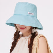 Model wearing a mint green wide-brim sun hat with a fabric label.