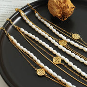 Three-layer gold and pearl bracelet displayed on a dark dish