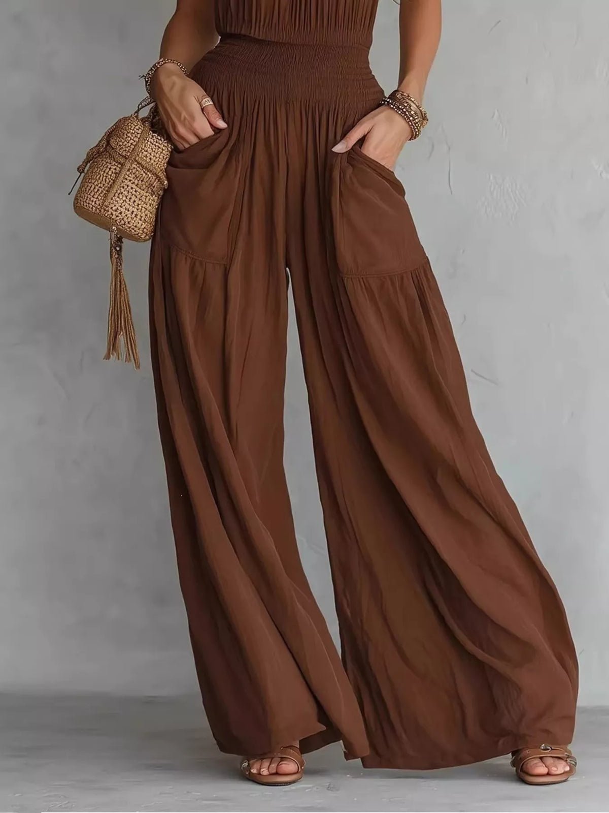 Close view of gathered smocked waist and roomy pockets on brown wide-leg jumpsuit