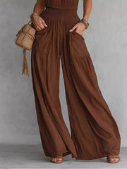 Close view of gathered smocked waist and roomy pockets on brown wide-leg jumpsuit