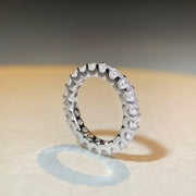 Pale pink oval center stone raised above the silver ring band, viewed from the side.