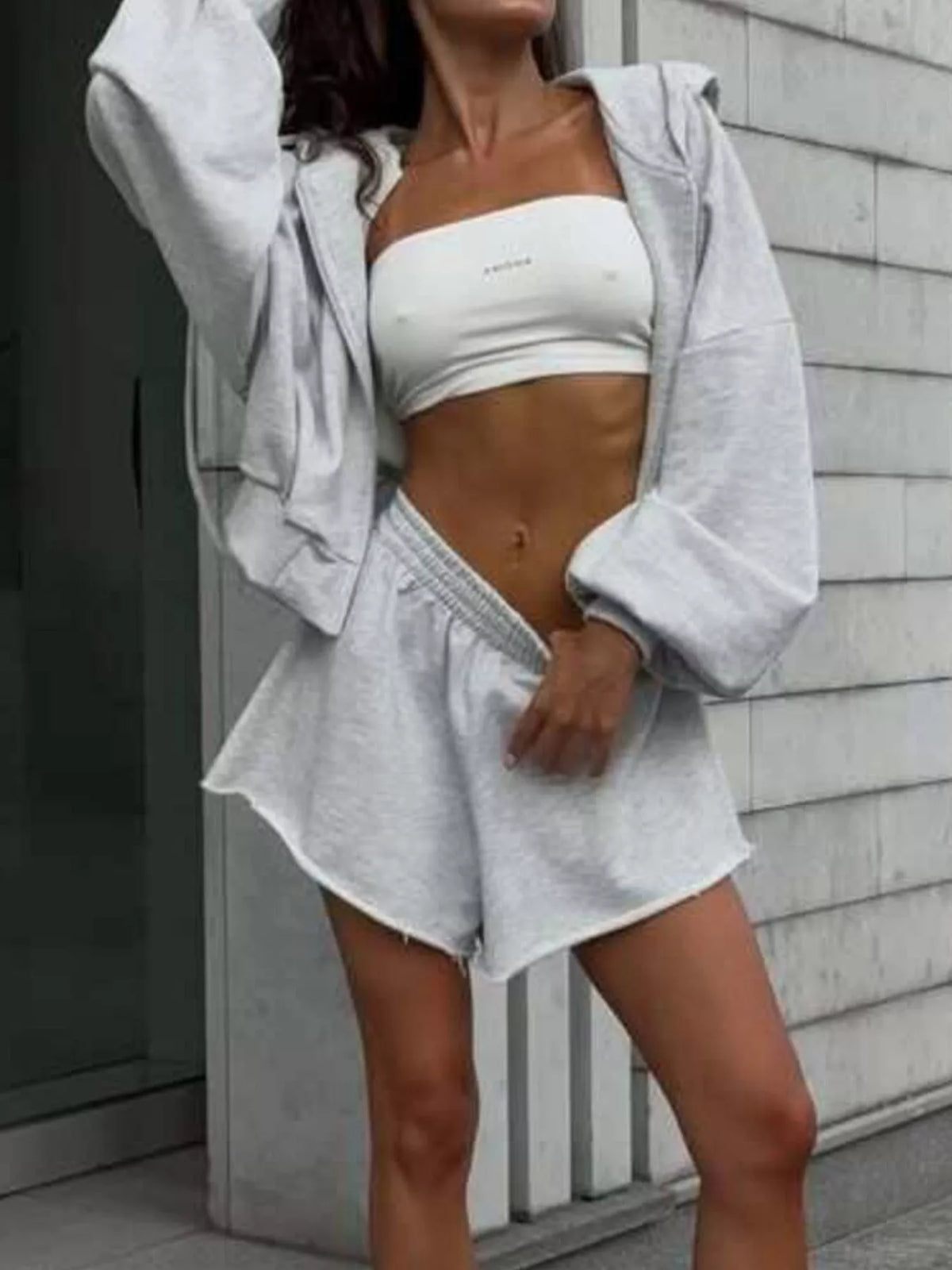 Model wearing light gray hoodie and shorts, seated
