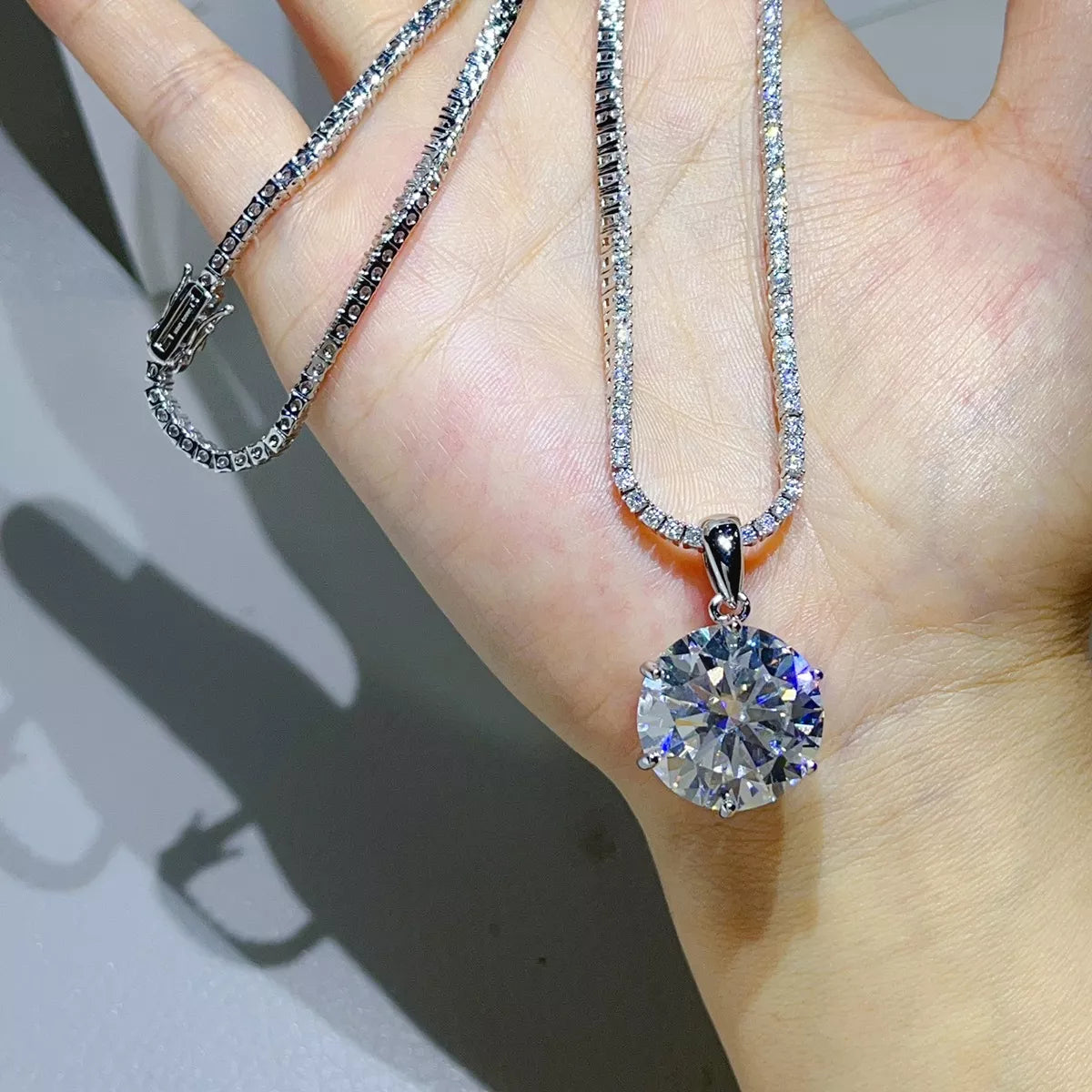 Round moissanite pendant necklace displayed across a hand