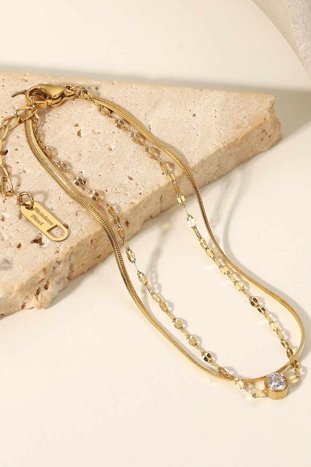 Double-layer gold bracelet with a bright central stone worn on the wrist