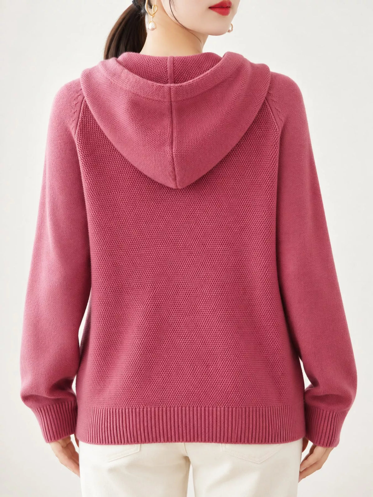 Back view of the dusty pink sweater showing its hood and ribbed hem.