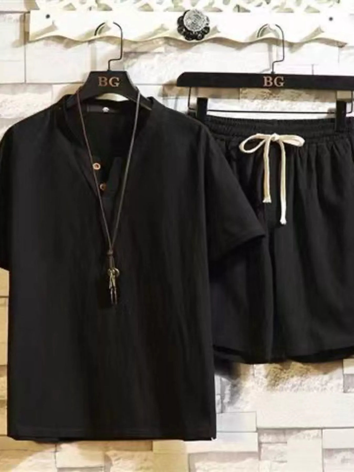 Black short-sleeve button-front shirt and matching drawstring shorts on hangers