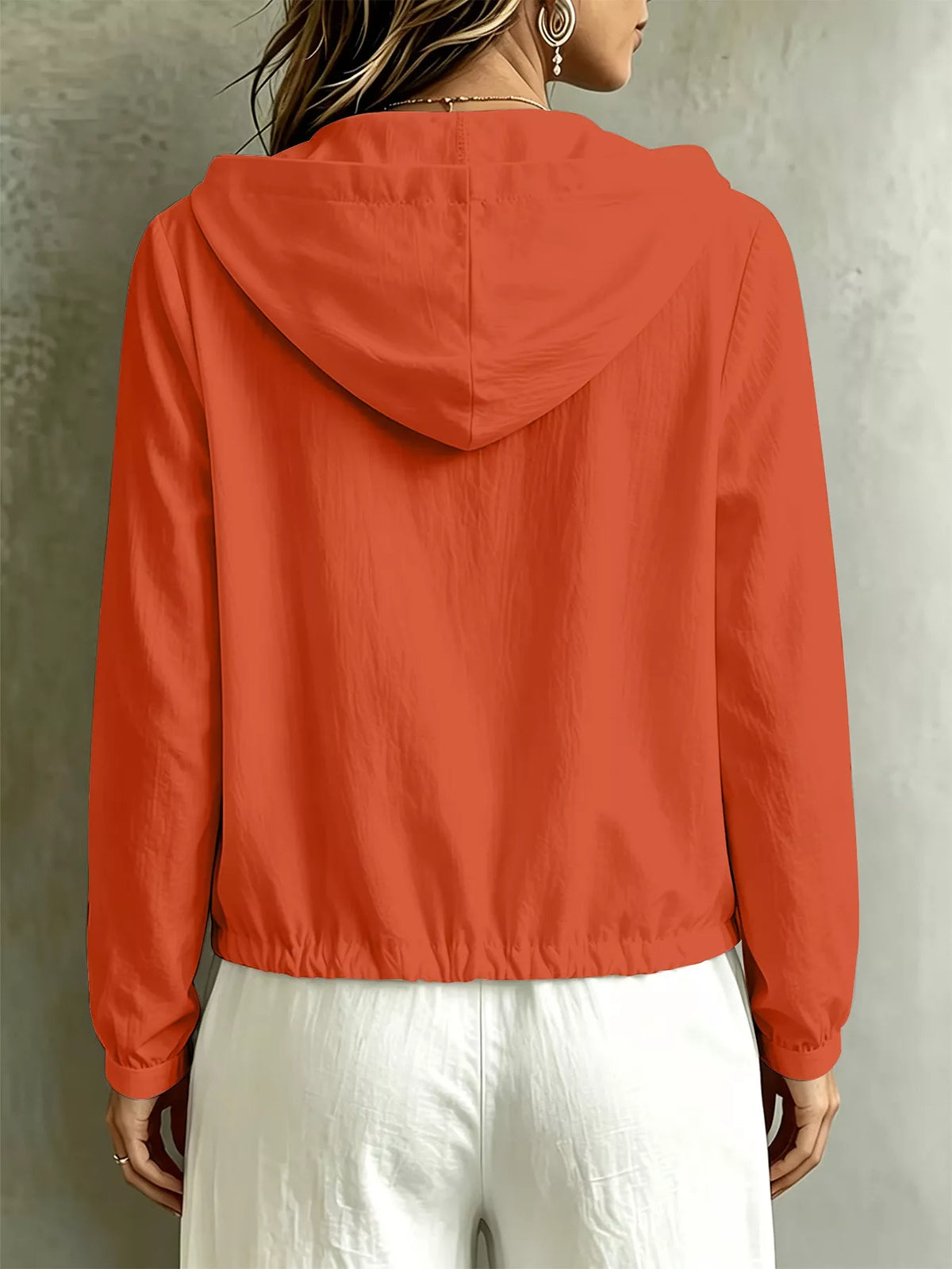 Back view of the coral blouse showing its hood and gathered hem.