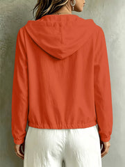 Back view of the coral blouse showing its hood and gathered hem.