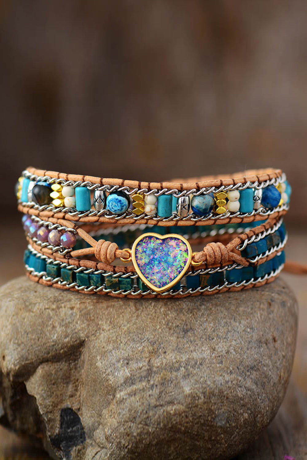 Colorful layered stone bracelet with a blue heart centerpiece displayed on a rock.