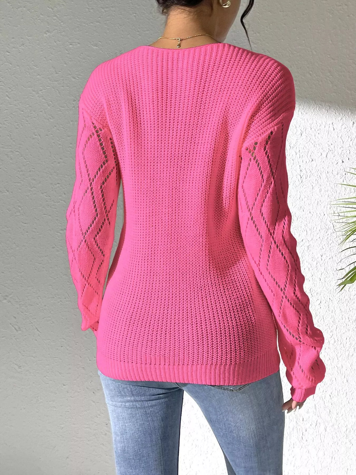 Back view of the pink sweater with plain knit body and diamond-pattern sleeves.