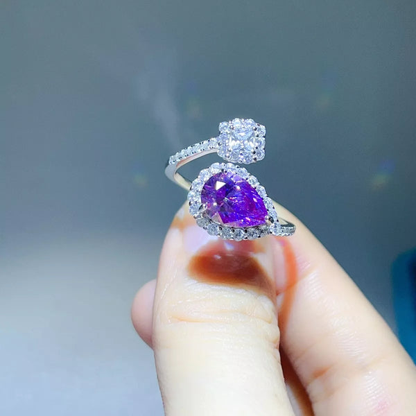 Angled view of the purple teardrop moissanite bypass ring held between fingers