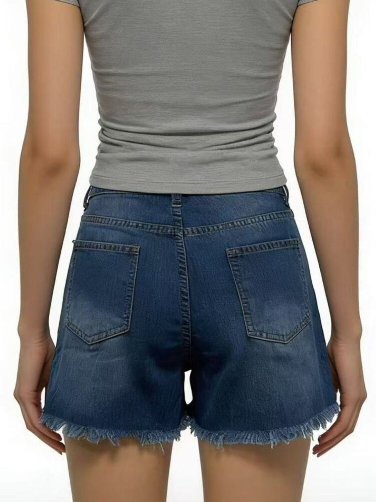 Back view of dark blue denim shorts with two patch pockets and raw hems, worn with a grey top