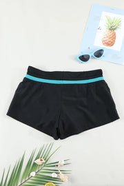 Back view of black swim shorts with a turquoise waistband stripe, laid flat.