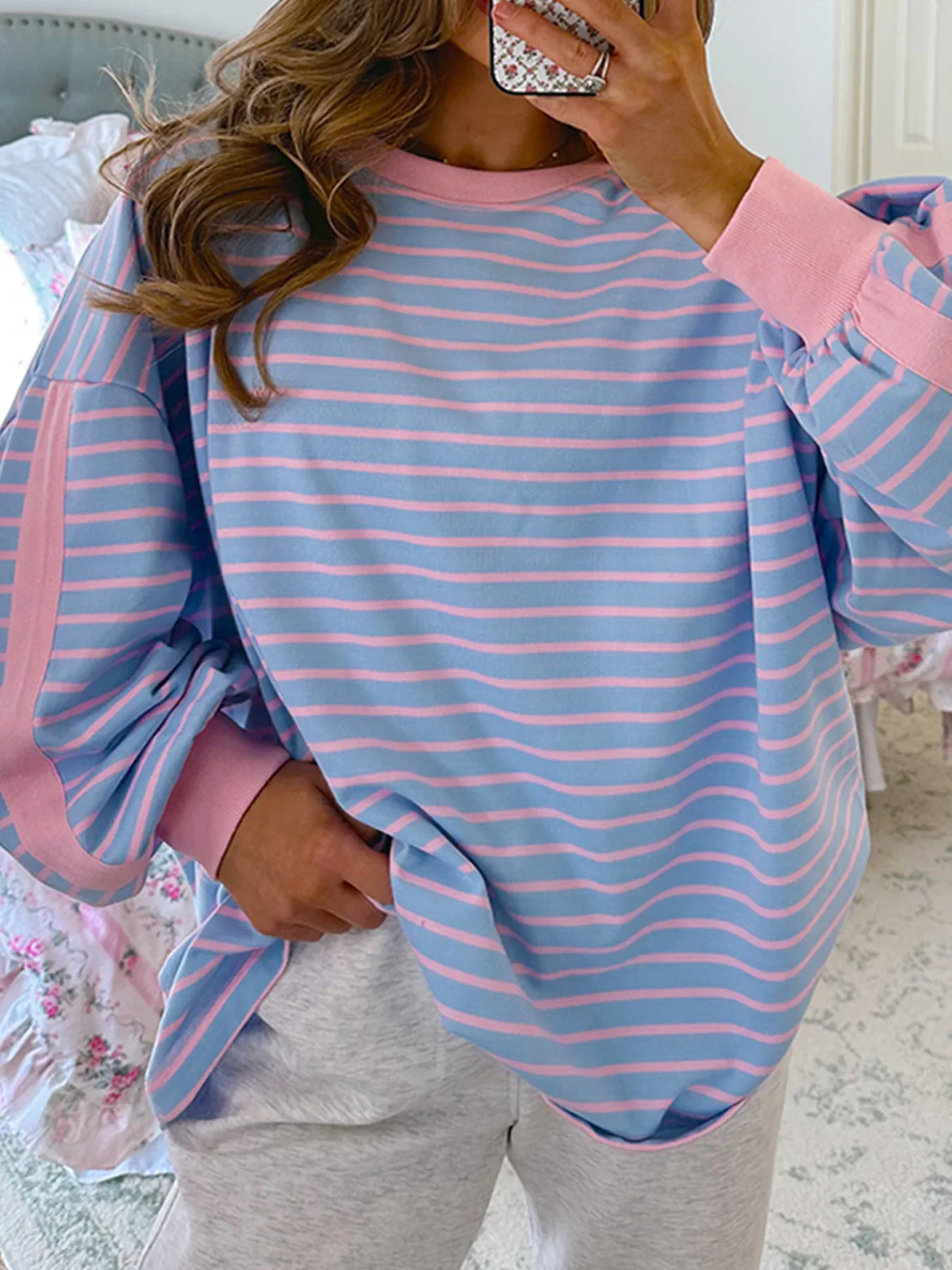 Model wearing blue and pink striped sweatshirt with contrast trim