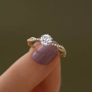 Close-up of a round zircon solitaire and decorative shoulders held between fingers