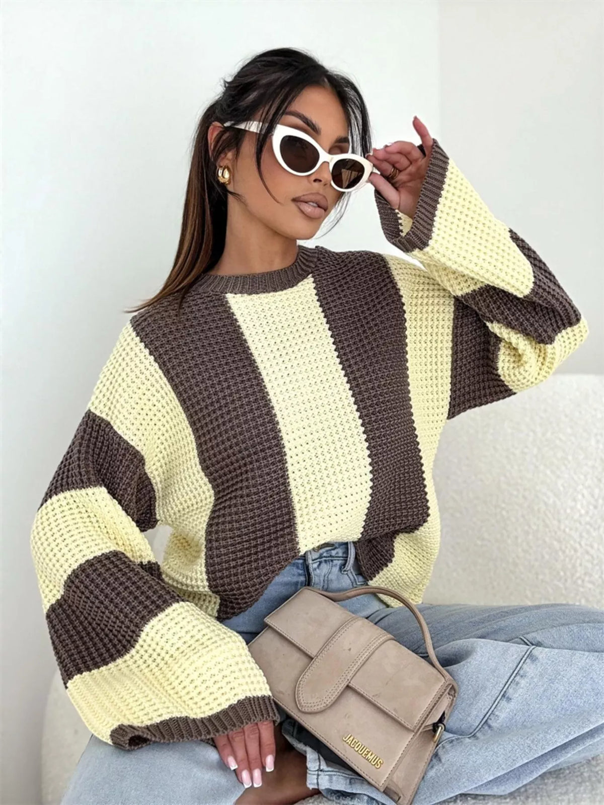 Seated model in cream and dark brown colour-block sweater with wide sleeves