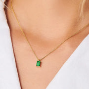 Green rectangular pendant necklace worn with an open white shirt