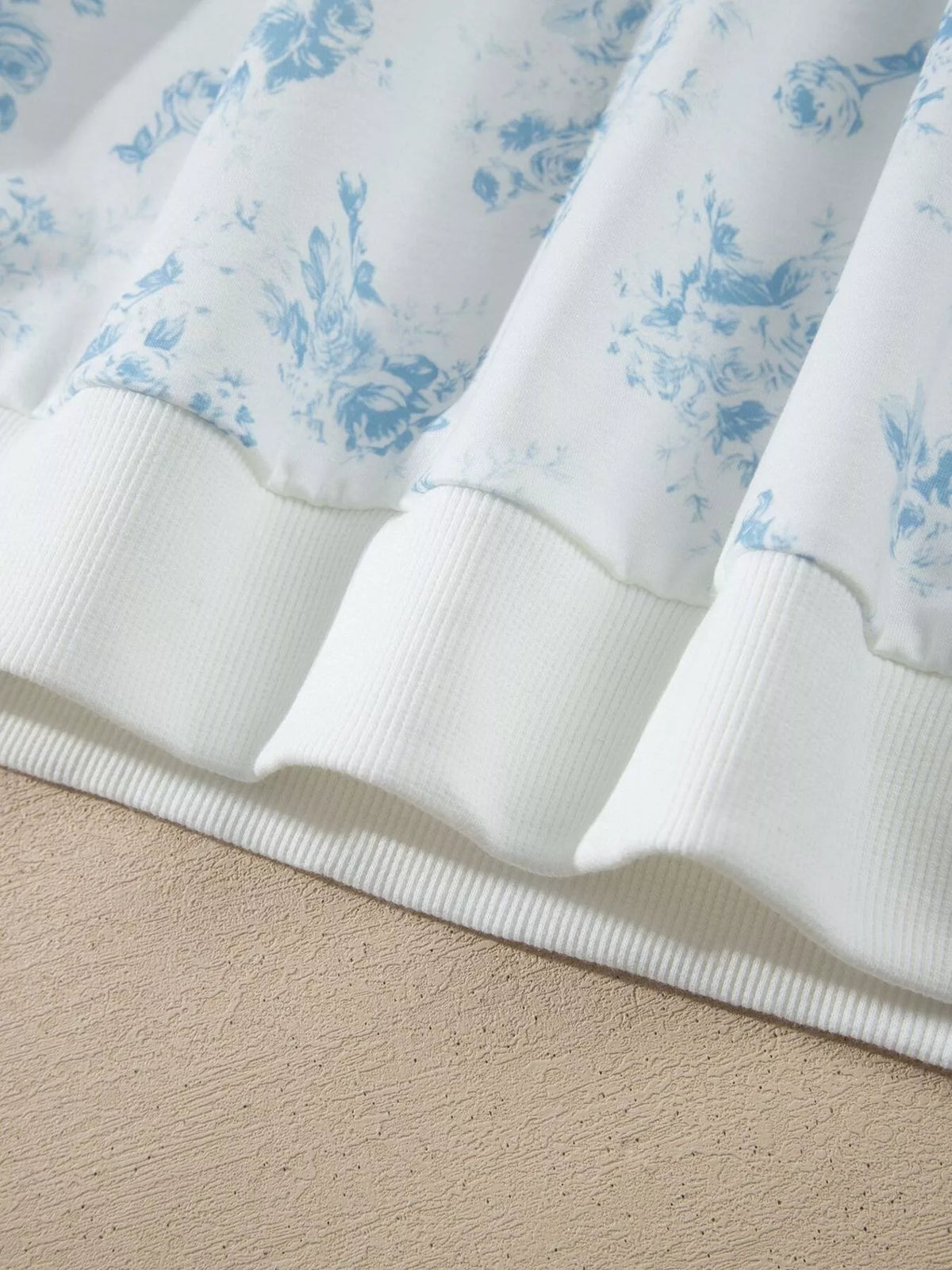 Close-up of white ribbed sweatshirt hem and blue floral print