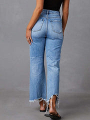 Back view of blue flare jeans with distressed details and raw hems.