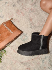 Black platform ankle boot styled beside a tan boot and accessories